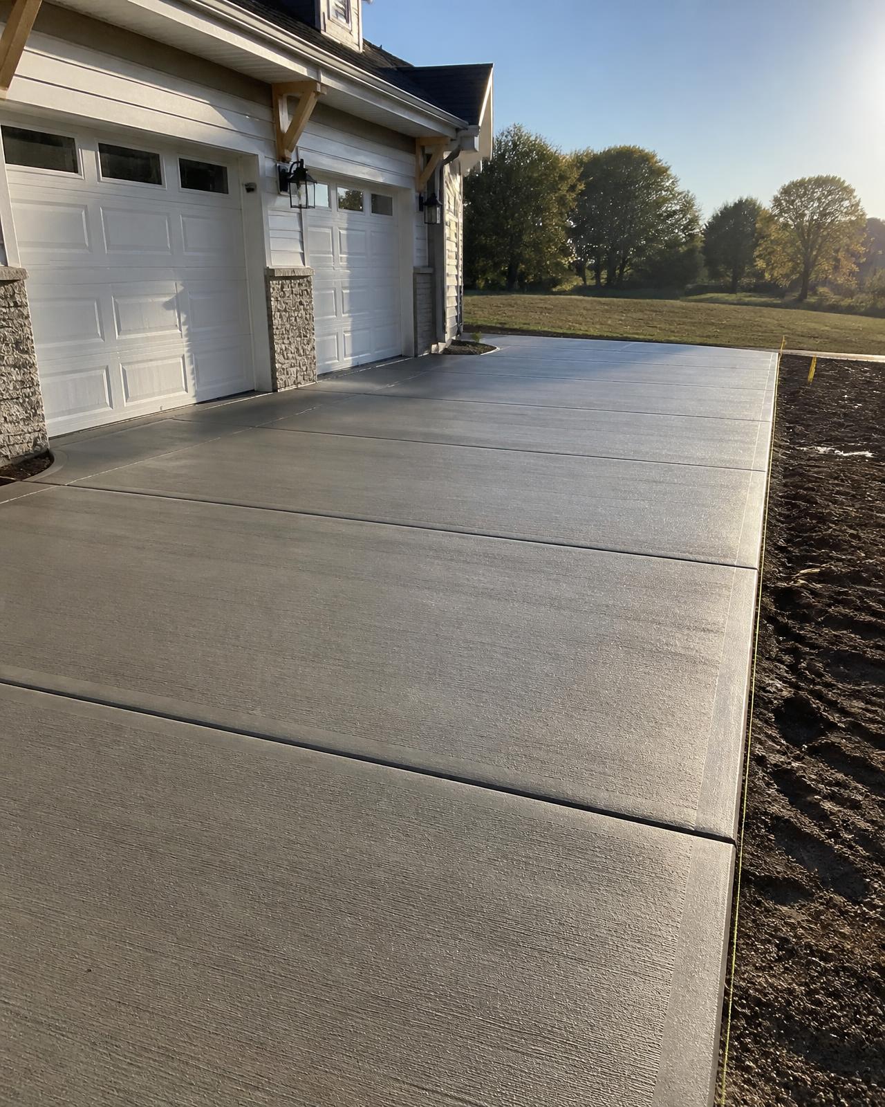 Freshly poured and brushed concrete driveway beside a new home
